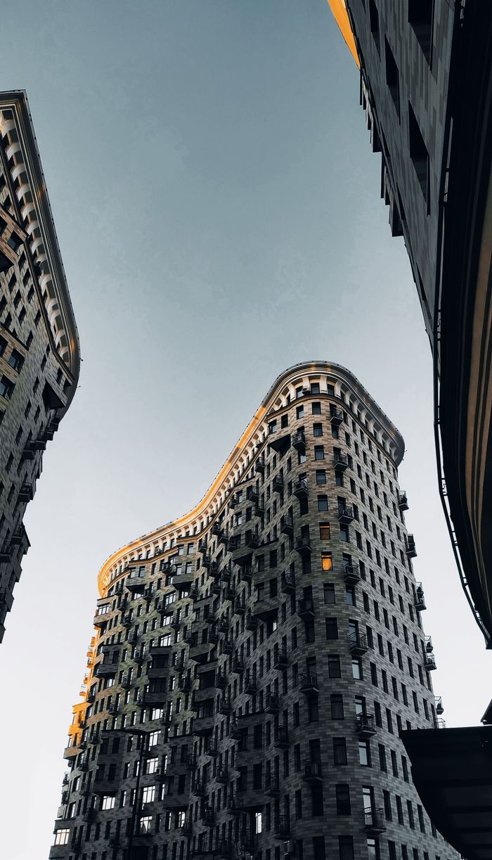 Low-angle view of a modern curved building in Moscow with a clear blue sky background.