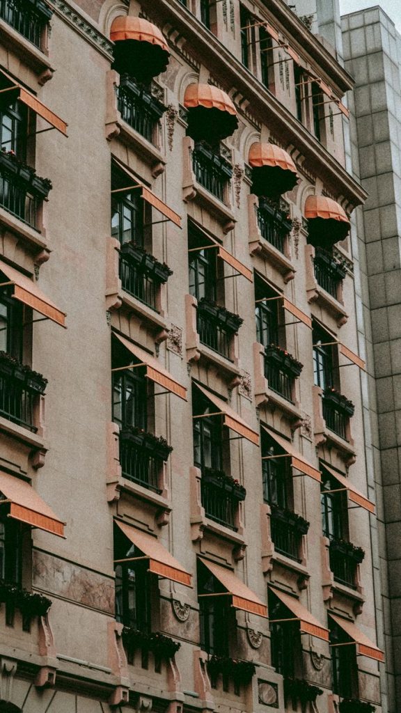 Close-up of a vintage building facade with ornate details and orange awnings in an urban setting.