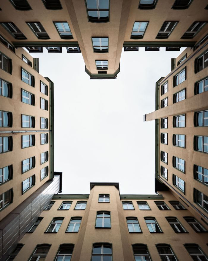 Looking up at symmetrical buildings in Berlin with clear sky above.